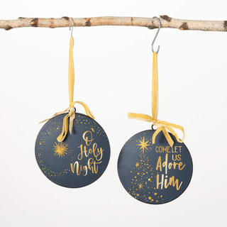 Two Christmas ornaments with gold text and ribbons hanging from a branch.
