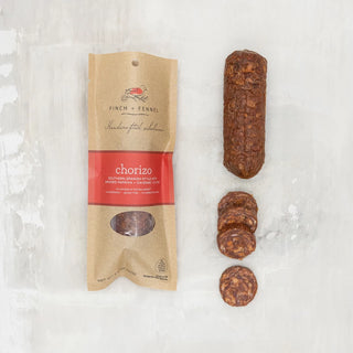 Packaged chorizo salumi next to its packaging, displayed on a white background, finch and fennel . Chorizo Salumi