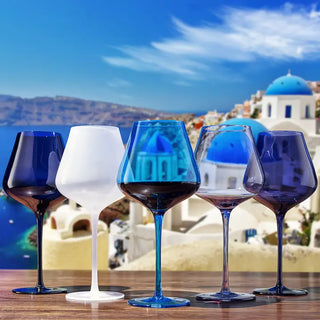 A set of five colored wine glasses in blue, clear, white, and purple, with a clear stem and base, filled with liquid.