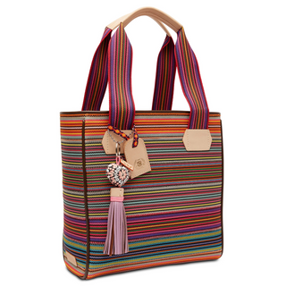 A multicolored woven tote bag with leather accents, a heart charm, and a tan handle.