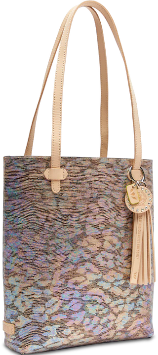 A textured leather tote bag with an iridescent jag print exterior, featuring a circular leather charm and tassel, and brown natural leather trim and handles.