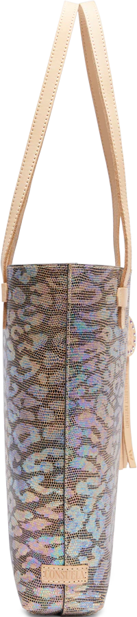 A textured leather tote bag with an iridescent jag print exterior, featuring a circular leather charm and tassel, and brown natural leather trim and handles.