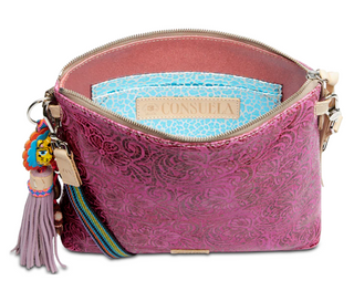 Purple textured handbag with decorative strap and tassel on a white background