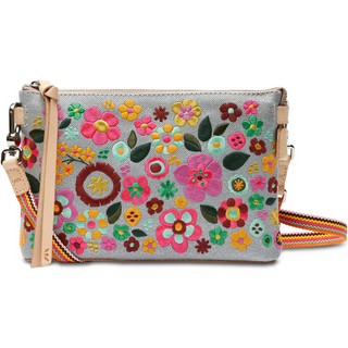 A floral embroidered Consuela Tink Midtown Crossbody handbag with multicolored flowers on a grey background, featuring a natural leather trim and a detachable woven strap.