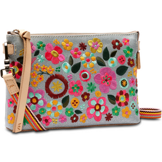 A floral embroidered Consuela Tink Midtown Crossbody handbag with multicolored flowers on a grey background, featuring a natural leather trim and a detachable woven strap.