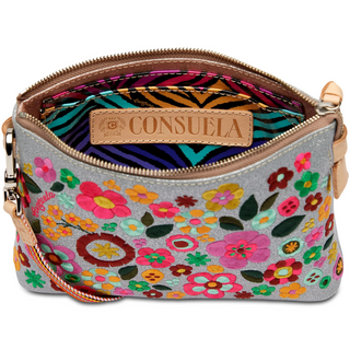 A floral embroidered Consuela Tink Midtown Crossbody handbag with multicolored flowers on a grey background, featuring a natural leather trim and a detachable woven strap.