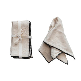 Two folded towels with black trim on a white background. Cotton Napkins with Edge Stitching, Natural & Black Set of 4