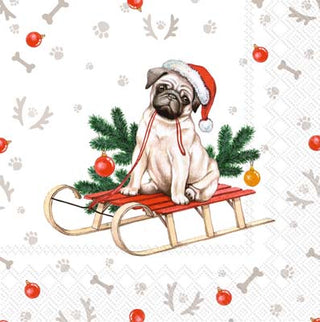 A cocktail napkin featuring an illustration of a dog wearing a Santa hat sitting on a sleigh, with a Christmas-themed pattern in the background.