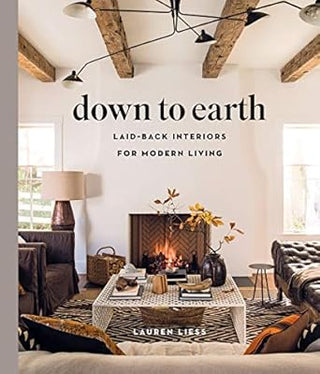 Cover of the book 'Down to Earth: Laid-back Interiors for Modern Living' by Lauren Liess, featuring a living room with a fireplace, wooden beams, and furniture arranged around it. Down to Earth.