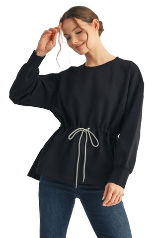 Woman wearing a black long-sleeve top with a drawstring waist on a beige background. Drawstring Waist Smooth Textured Top in Black
