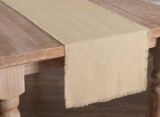 A beige burlap table runner placed on a wooden table.