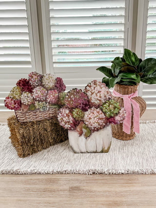 Fall Hydrangea Pumpkin Basket Stake Assorted
The set includes a wicker basket with pink and burgundy hydrangea-style blooms on a brown woven base, a central white ceramic pot with pink and green hydrangea-style blooms metal pink green white