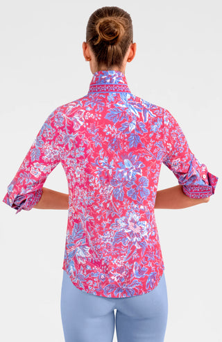 A woman wearing a pink and purple floral boyfriend shirt with long sleeves, shell buttons, and a collar.