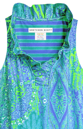 A woman wearing a sleeveless, ruffle neck, turquoise print dress with a stand-up collar.