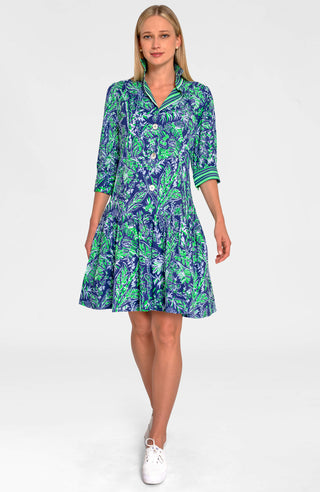 A woman wearing a navy dress with a green leaf pattern. The dress has long sleeves, a V-neck, and a flared skirt.