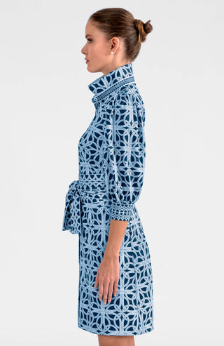 A model wearing a navy and white geometric patterned dress with a mandarin collar, puff sleeves, and a belt.