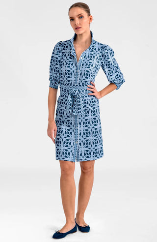 A model wearing a navy and white geometric patterned dress with a mandarin collar, puff sleeves, and a belt.