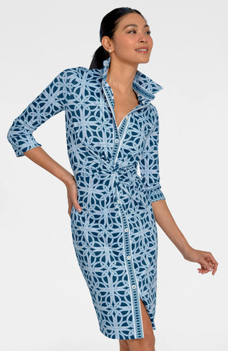 A woman wearing a navy dress with a geometric pattern, featuring 3/4 sleeves and a mandarin collar.