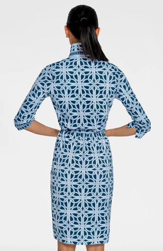 A woman wearing a navy dress with a geometric pattern, featuring 3/4 sleeves and a mandarin collar.