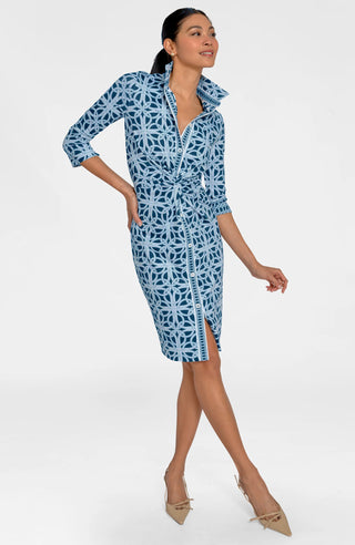 A woman wearing a navy dress with a geometric pattern, featuring 3/4 sleeves and a mandarin collar.