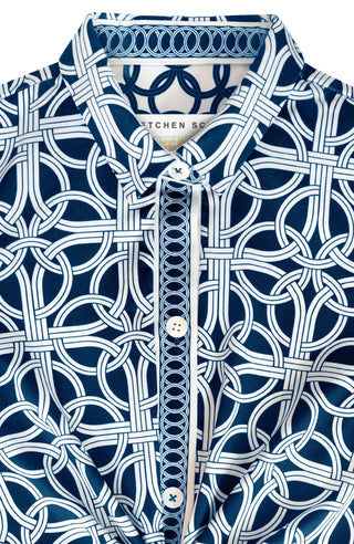 A woman wearing a navy dress with a geometric pattern, featuring 3/4 sleeves and a mandarin collar.