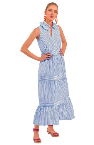 A model wearing a blue Gretchen Scott wash and wear hope midi/maxi dress with a double pleated collar, tiered banded gathered skirt, elasticized waist, side seam pockets, and coordinating inside back panel.