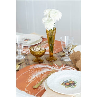 Decorative table setting with a pumpkin-themed placemat, white flowers in a vase, and other tableware.