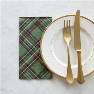 A green plaid guest napkin is placed on a white plate with a golden fork and a golden knife on top of a marble surface.