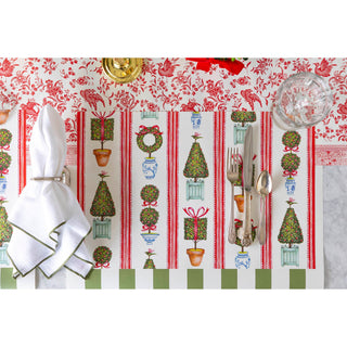 Decorative placemat with Christmas-themed design featuring trees, wreaths, and ribbons on a white background.
