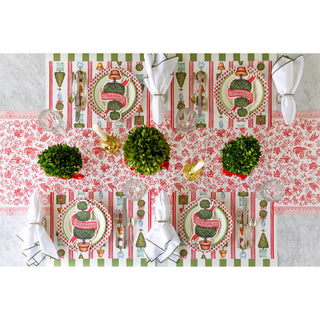 Decorative table setting with a red and white patterned tablecloth, greenery, and white napkins.
