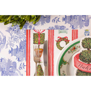 Christmas-themed table setting with patterned placemat, plates, and cutlery.