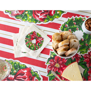 Christmas-themed table setting with bread, cheese, and a decorative napkin on a festive tablecloth.
