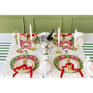 Elegant Christmas table setting with decorative plates, candles, and a bottle of wine.