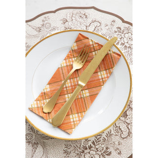 Plated setting with gold fork and knife on an orange checkered napkin.