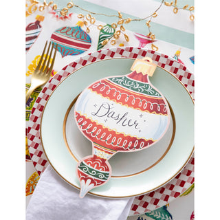 Christmas-themed place setting with a decorative ornament name card on a plate.