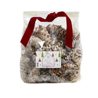 A clear plastic bag filled with beige and white pine cones, tied with a red ribbon at the top and adorned with a festive label that reads 'Merry & Bright'.