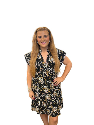 Woman wearing a black dress with gold PINK  floral patterns 