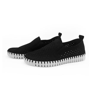 A pair of black slip-on shoes with a laser cut pattern and a flexible outsole, designed by Ilse Jacobsen.