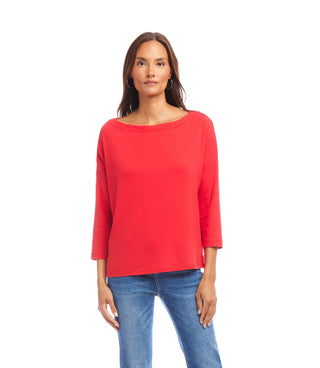 A woman wearing a red 3/4 sleeve boatneck top with blue jeans.