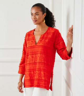 A woman wearing an orange tunic with 3/4 length sleeves and embroidery details.
