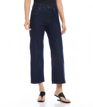 A person standing wearing Karen Kane Cropped Wide Leg Jeans in a dark wash, paired with a black top and black sandals.