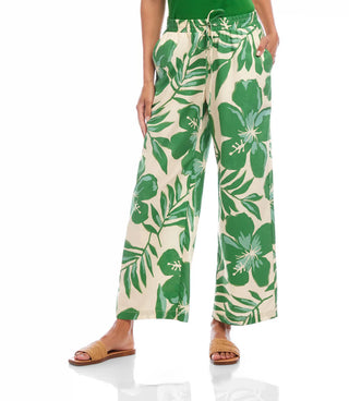 Tropical leaf-patterned pants worn by a person on a white background
