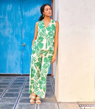 Woman wearing a green leaf-patterned jumpsuit standing in front of a blue door.