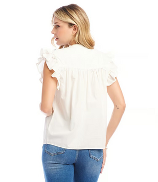 A woman wearing an off white top with navy blue embroidered ruffle sleeves and a split neck.