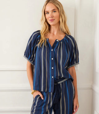 Woman wearing a blue striped outfit against a white wall