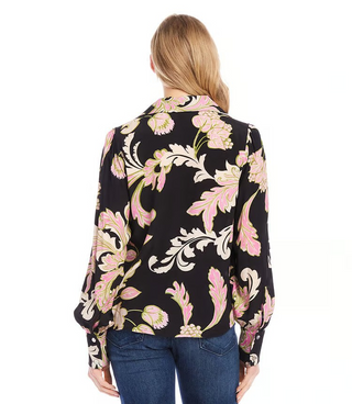 A woman wearing a black floral print blouson V-neck top and blue jeans.