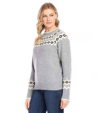 A woman wearing a gray jacquard knit sweater with geometric patterns on the sleeves, paired with blue jeans.