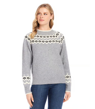 A woman wearing a gray jacquard knit sweater with geometric patterns on the sleeves, paired with blue jeans.