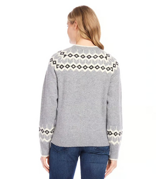 A woman wearing a gray jacquard knit sweater with geometric patterns on the sleeves, paired with blue jeans.