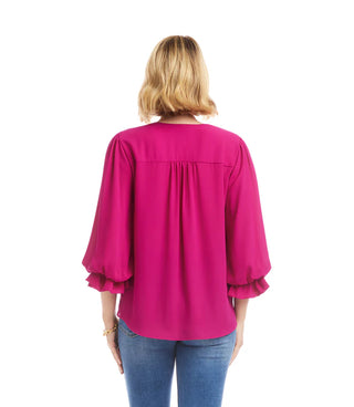 Person wearing a bright pink blouse with ruffled sleeves on a white background. Karen Kane Layered Sleeve Asymmetric Top, Magenta